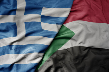 big waving national colorful flag of greece and national flag of sudan .