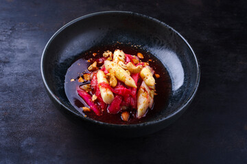 German rhubarb asparagus salad with cashew nuts in raspberry sauce served as close-up in a Nordic design bowl with copy space 