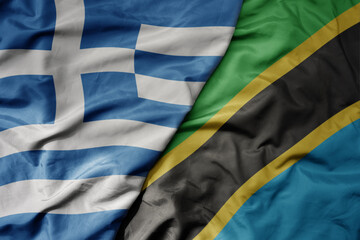 big waving national colorful flag of greece and national flag of tanzania .