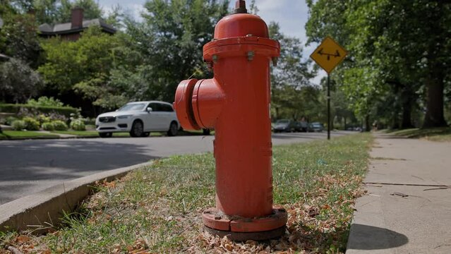 Handheld slow motion view of vintage looking red fire hydrant with rust in classic suburban sidewalk and middle class neighborhood near road and street