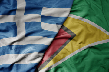 big waving national colorful flag of greece and national flag of guyana .