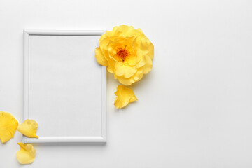 Blank photo frame with yellow flower on light background