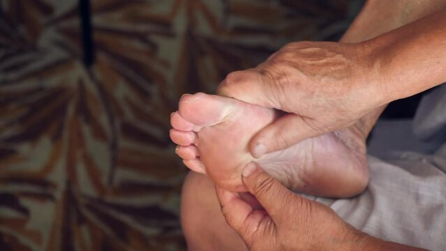 an old woman without a face massages her foot, making the skin of her feet smooth, close-up, slow motion.