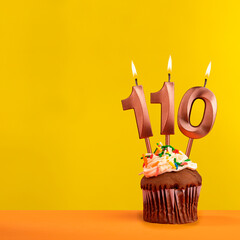 Candle with flame number 110 - Birthday card on yellow background