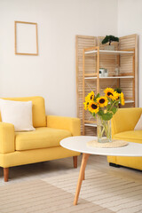 Vase with beautiful sunflowers and yellow armchair in interior of stylish living room