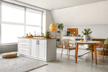 Interior of modern kitchen with white counters and dining table