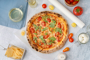 Tasty pizza Margarita with tomatoes and arugula on light blue table