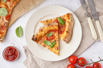 Plate with pieces of tasty pizza Margarita and basil on white table
