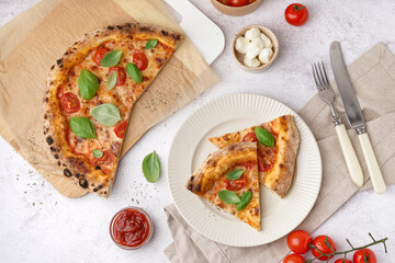 Plate with pieces of tasty pizza Margarita and basil on white table