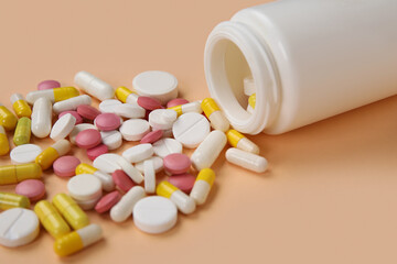 Jar with different scattered pills on orange background