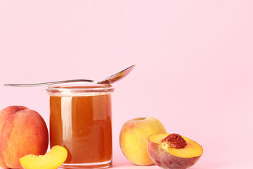 Jar with sweet peach jam and fresh fruits on pink background