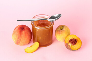 Jar with sweet peach jam and fresh fruits on pink background