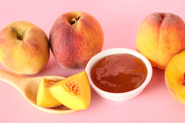 Bowl with sweet peach jam and fresh fruits on pink background