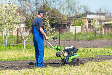 Farmer man plows the land with a cultivator preparing the soil for sowing