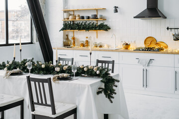 Christmas decor on the kitchen with garland. Festive home interior. Christmas table setting over Defocused lights Scandinavian style