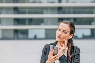 Fototapeta premium business woman with mobile phone and expression of doubt, decision or mistrust