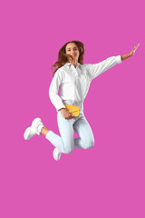 Young woman jumping on pink background
