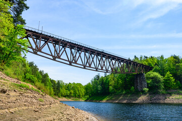 Railway bridge over Lake Pilchowickie, currently closed railway line. Bottom view of the metal structure of the bridge from the shore of the lake.