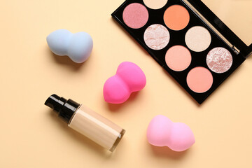 Obraz na płótnie Canvas Set of makeup sponges, liquid foundation and eyeshadows on color background