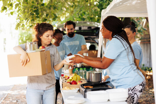 Diverse group of volunteers happily distributing food to the needy. Smiles and genuine happiness all around as they provide donations to homeless individuals and seniors facing poverty.