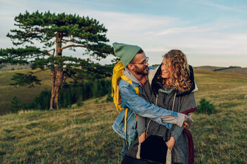 Couple of hikers hugging while walking on a mountain trail during a vacation