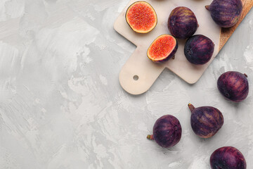 Board with fresh ripe figs on grey background