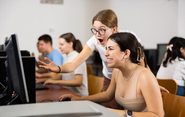Amazed female students looking at the screen of PC while learning computer science in the classroom