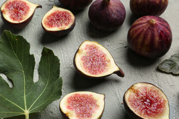 Fresh ripe figs and leaf on grey background