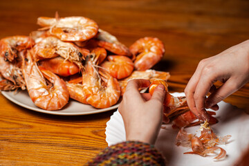 Large cooked king prawns on the table. An unrecognizable man is eating shrimp at the table.