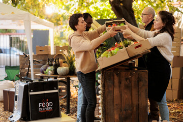 Fruit and vegetable seller giving organic produce box to young delivery girl. Female courier...