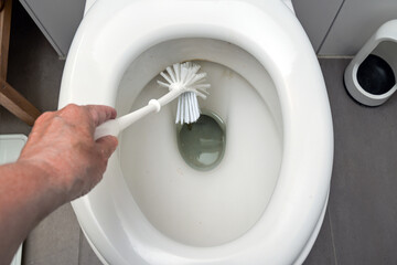 Hand is cleaning a disgusting dirty toilet with a brush, hygiene for health in the household, copy...
