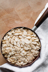 overhead view of nigerian egusi seeds in a brown bowl, shelled melon seeds in a bowl, nigerian melon seeds, pumpkin seeds for cooking