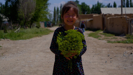Cute little girl holding dill in her hands and smiling