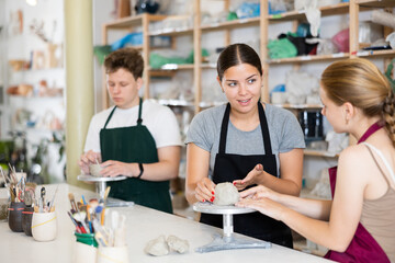 Potter helps young apprentices mold pottery from clay in a workshop