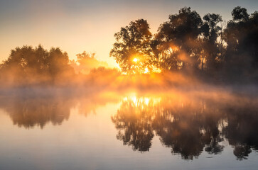 Misty sunrise over calm lake