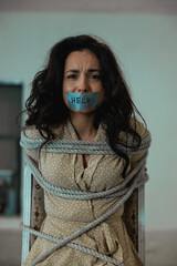 Frightened woman with tape on her mouth with the inscription help, looking at camera. tied with a...