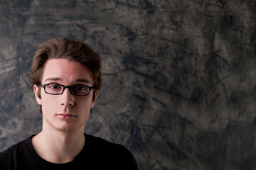 Nerd challenges logic, beside empty chalkboard copyspace