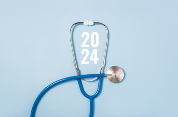 Stethoscope and white numbers 2024 on blue background. Concept of health care in the New Year. Medical calendar. Copy space