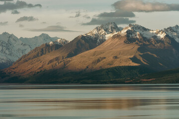 Lake at sunset surrounded by snow capped mountains