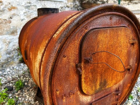 Old Distressed Abandoned Burnt Burning Hot Seared Rusty Corrosion Brown Iron Metal Barrel Can Industrial Drum Waste Burner Firebox with Fuel & Oxygen Ash Pan Damper Draft Door against Cold Stone Wall