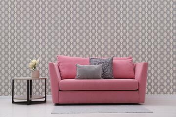 Comfortable pink sofa and side table near wall. Minimalist living room interior