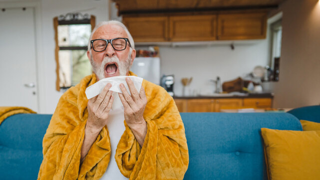 one senior man sit on sofa bed hold Paper tissue common cold sneezing - Powered by Adobe