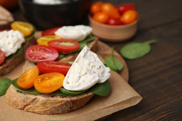 Delicious sandwiches with burrata cheese and tomatoes on wooden table, closeup. Space for text