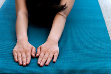 young woman is stretching out on a yoga mat in a sitting forward fold position