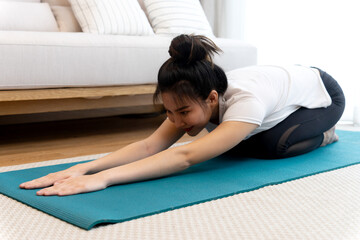 young woman is stretching out on a yoga mat in a sitting forward fold position