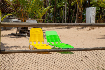 Cadeiras de praia verde e amarela, nas cores do Brasil, vazias na areia em um dia ensolarado de...