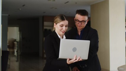 Colleagues walking along the office corridor and discussing a new startup project. Business man businessman talking to attractive assistant about their business. - Powered by Adobe
