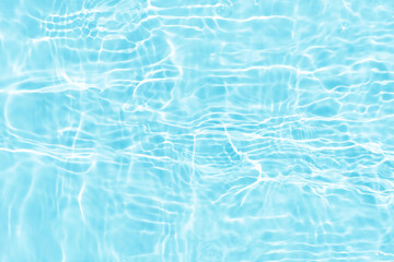 Blue water with ripples on the surface. Defocus blurred transparent blue colored clear calm water surface texture with splashes and bubbles. Water waves with shining pattern texture background.