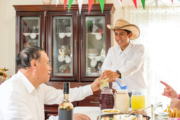 Grandfather receiving a glass of pineapple water from his grandson during a family reunion