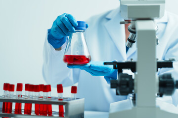 Close up dedicated hematology lab technician scrutinizing blood sample analysis under microscope,...